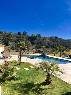 Un espace piscine offrant une vue dégagée sur le paysage environnant, notamment sur les arbres et un bâtiment situé au loin.