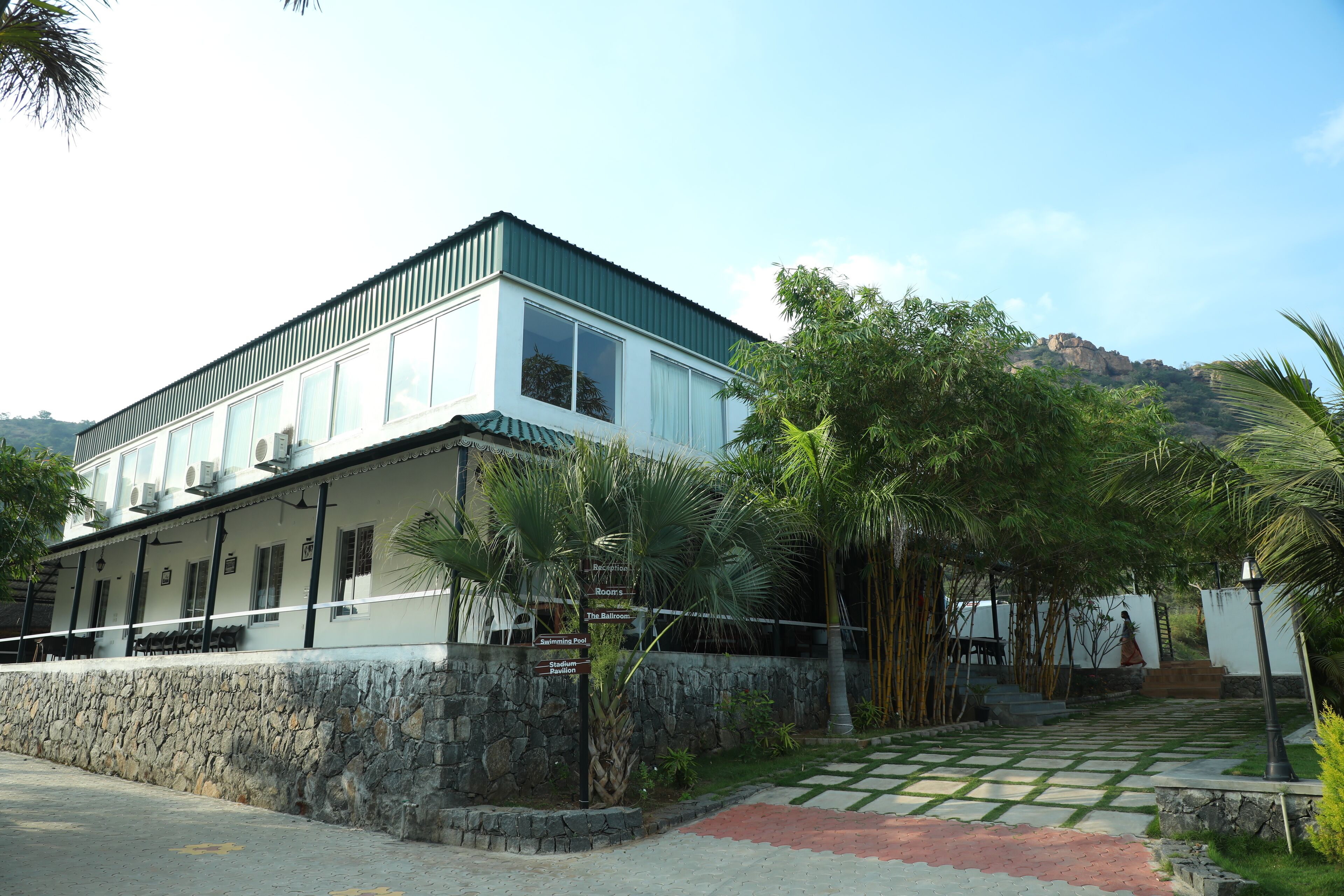 A two-story building with a stone wall and a green roof.