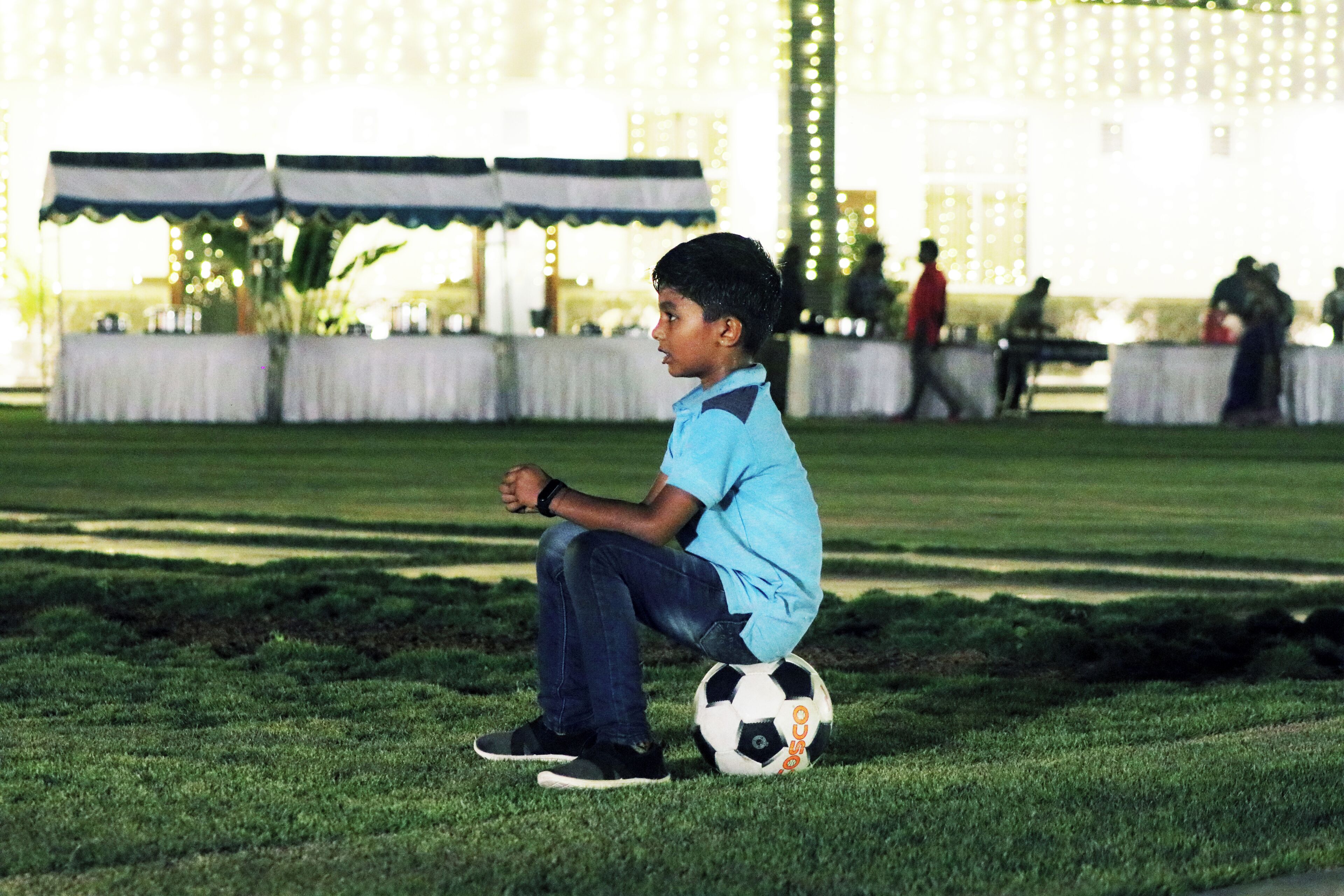 Un niño sentado sobre la hierba con un balón de fútbol.