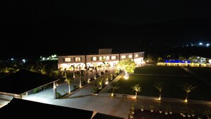 A well-lit hotel with a large outdoor area, including a pool and palm trees. - Forest Meadows Resort -Swiss In Salem (Salem)