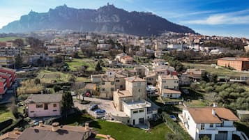 Un quartiere residenziale con un mix di architettura moderna e tradizionale, con una collina che si staglia sullo sfondo, caratterizzata da una struttura simile a una fortezza.