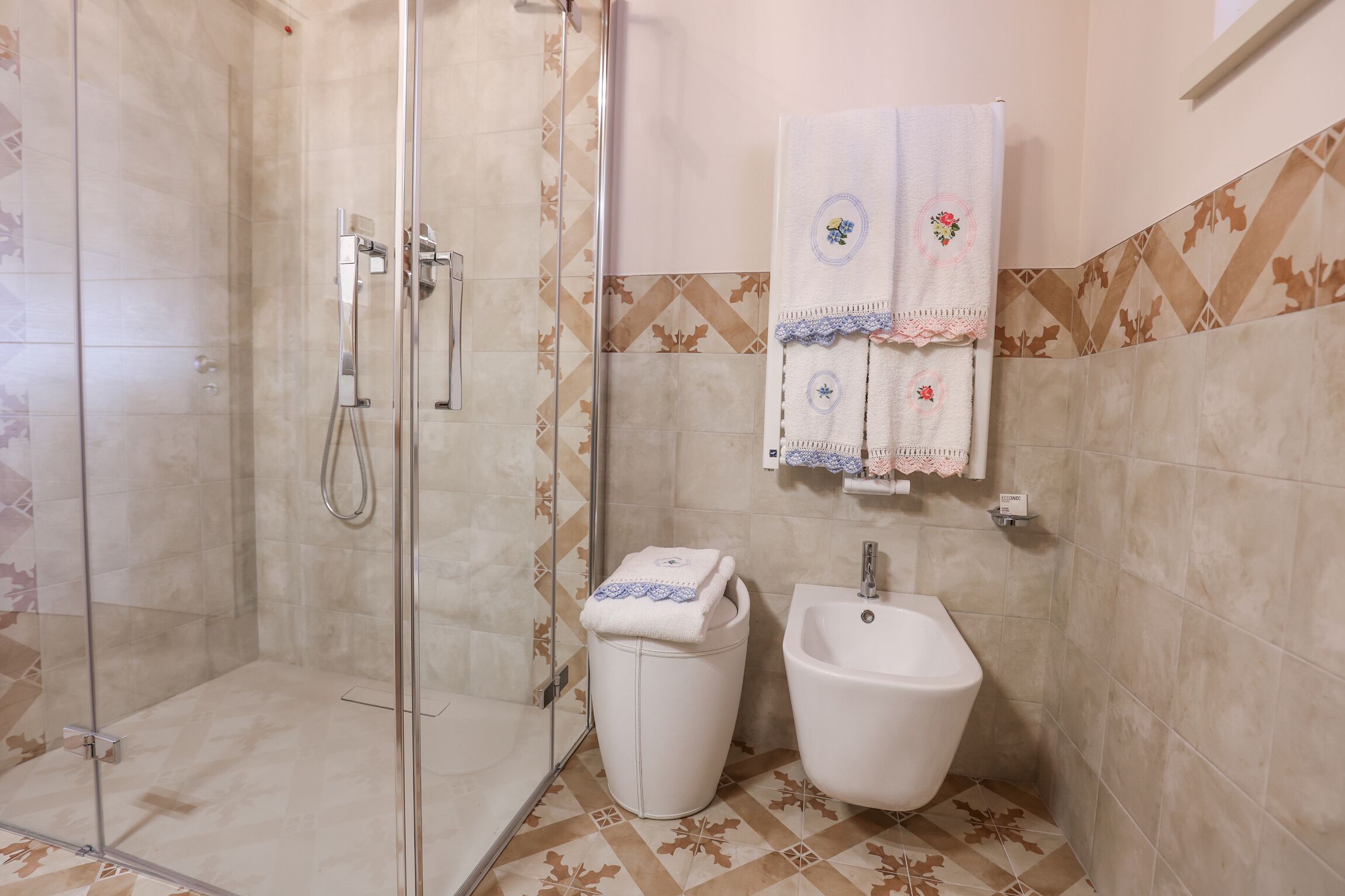 A bathroom with a glass-enclosed shower, a bidet, and a sink.