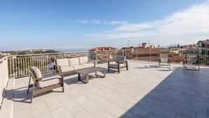 Terraza en la azotea con mobiliario exterior, vista panorámica de la ciudad y cielo despejado.