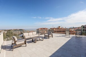 Terraza en la azotea con mobiliario exterior, vista panorámica de la ciudad y cielo despejado.