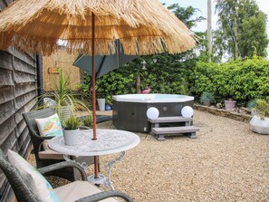 A patio area with a thatched umbrella, wicker furniture, a hot tub, and potted plants. - The Loft (Shrewsbury)