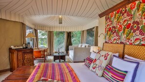 Ein geräumiges Schlafzimmer mit einem großen Bett, einer Sitzecke, einem Schreibtisch und Blick ins Freie.