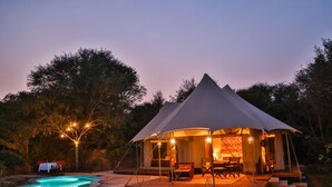 Eine Zelthotellage mit Pool, Sitzgelegenheiten im Freien und Essbereich.