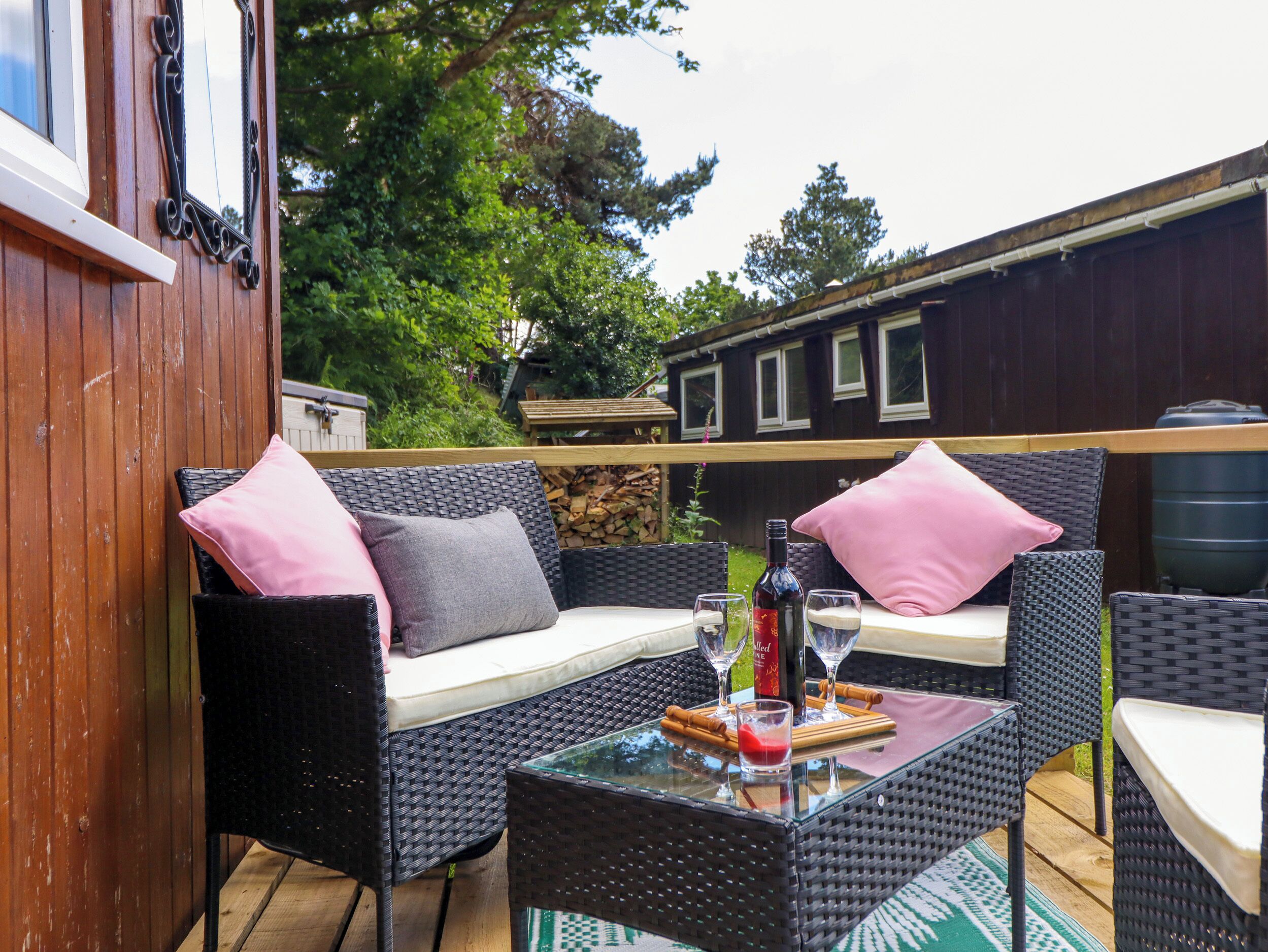 An outdoor seating area with wicker furniture, a glass table, and a bottle of wine.