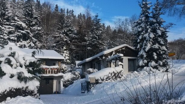 Un quartiere residenziale innevato, con case e cielo sereno.