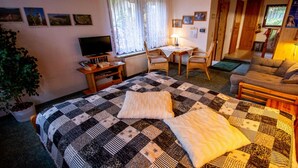 Una camera accogliente con un letto, una scrivania, una sedia, una televisione e una pianta.