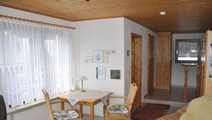 Un accogliente soggiorno con un tavolino di legno, due poltrone, una televisione e un camino.