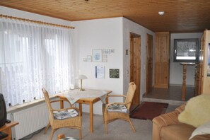 Ein gemütliches Wohnzimmer mit einem Holztisch, zwei Stühlen, einem Fernseher und einem Kamin.