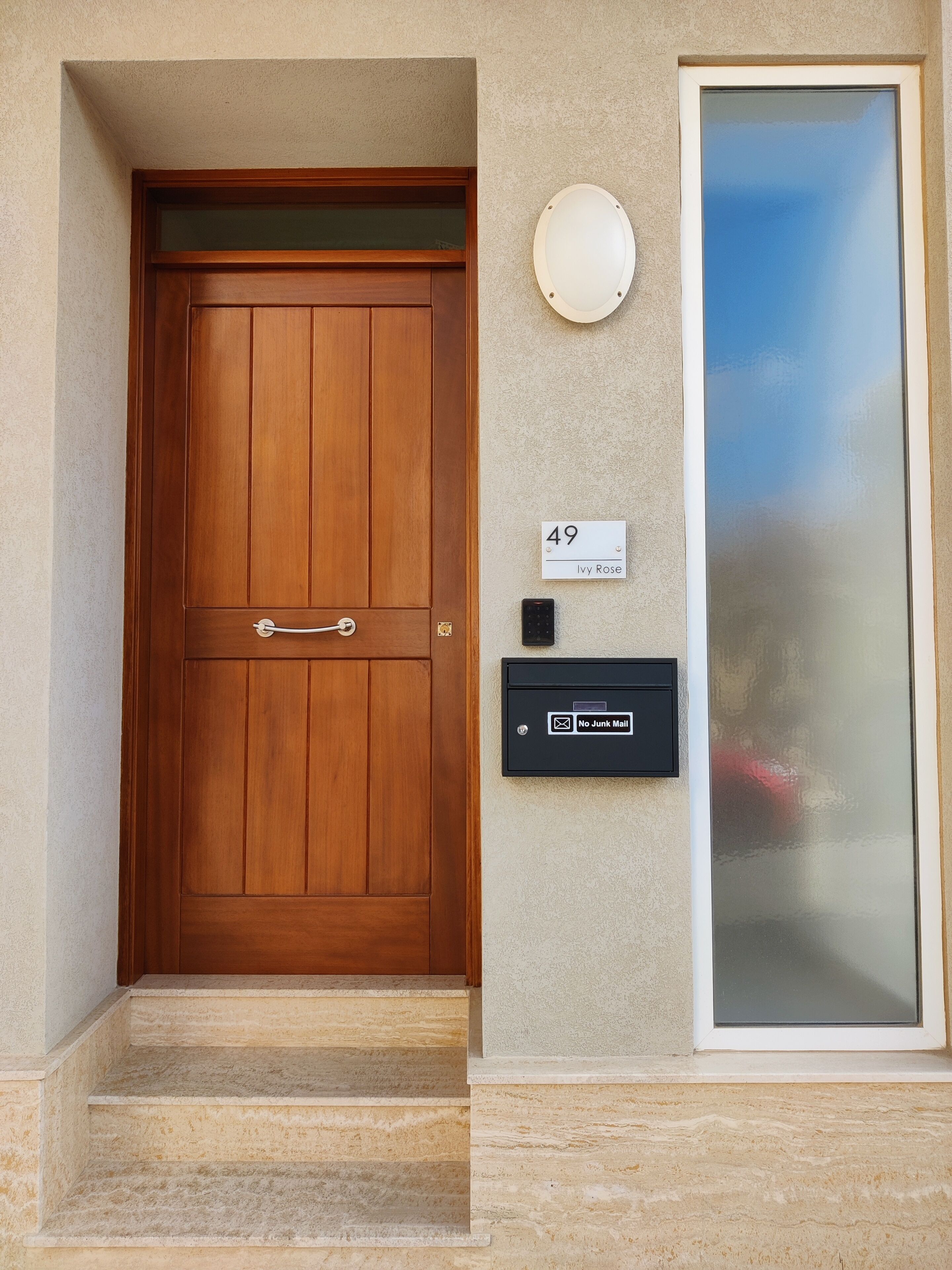 Une porte d’entrée en bois avec une boîte aux lettres et une plaque de numéro de maison.