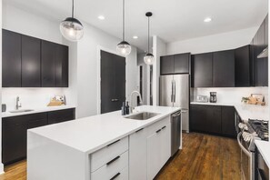 A modern kitchen with black cabinets, white countertops, stainless steel appliances, and pendant lighting. - Rooftop Deck & Garage, 2 miles Downtown Broadway (Nashville)