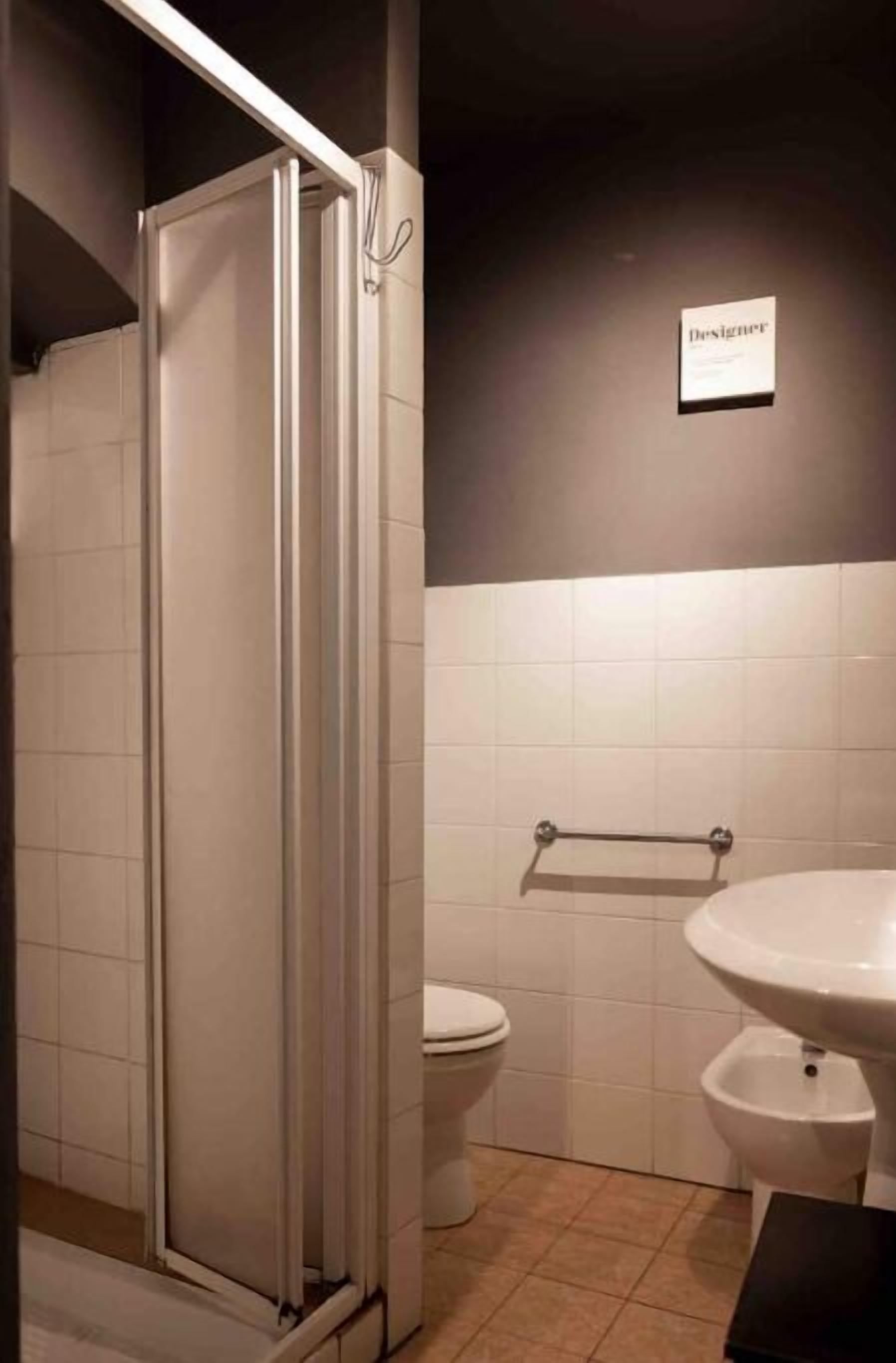 A bathroom with a shower enclosure, toilet, bidet, and a sink.