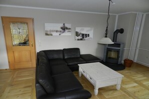 A living room with a sectional sofa, a white coffee table, a fireplace, and wall art.
