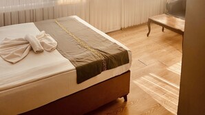 Ett hotellrum med en säng, en stol och tunna, genomskinliga gardiner.