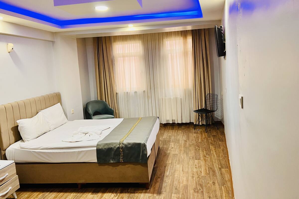 A hotel room with a bed, a chair, a desk, and a TV.