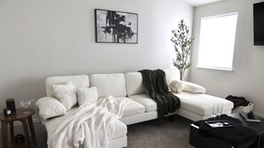 Ett modernt vardagsrum med en vit soffa, ett svart soffbord och ett sidobord.