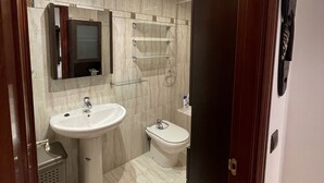 A modern bathroom with a sink, toilet, and mirror.