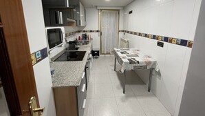 A compact kitchen with a microwave, stove, sink, and a small dining table.