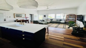 A spacious living area with a large island, a sofa set, and a ceiling fan. - Bowen Beach House Absolute beachfront family holiday home (Bowen)