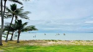 A beach with palm trees, a sandy shore, and sailboats on the water. - Bowen Beach House Absolute beachfront family holiday home (Bowen)