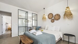 A modern bedroom with a bed, bedside tables, a bench, and decorative wall hangings. - Casa do Cacto - By Wehost (Porto Santo)