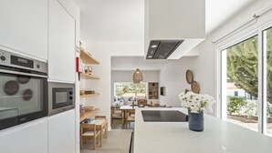 A modern kitchen with white cabinetry, a built-in oven, and a large window. - Casa do Cacto - By Wehost (Porto Santo)