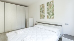 A bedroom with a bed, a wardrobe, and a nightstand.