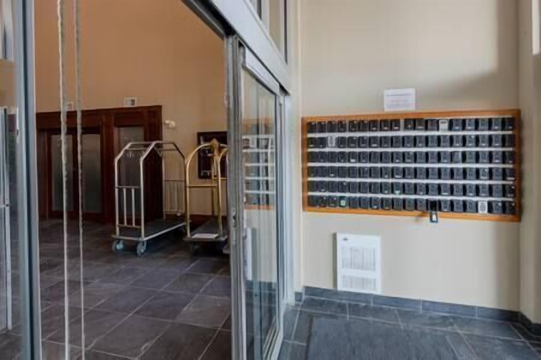 A hotel lobby with a glass door entrance, a tiled floor, and a wall displaying a row of black and white photographs.