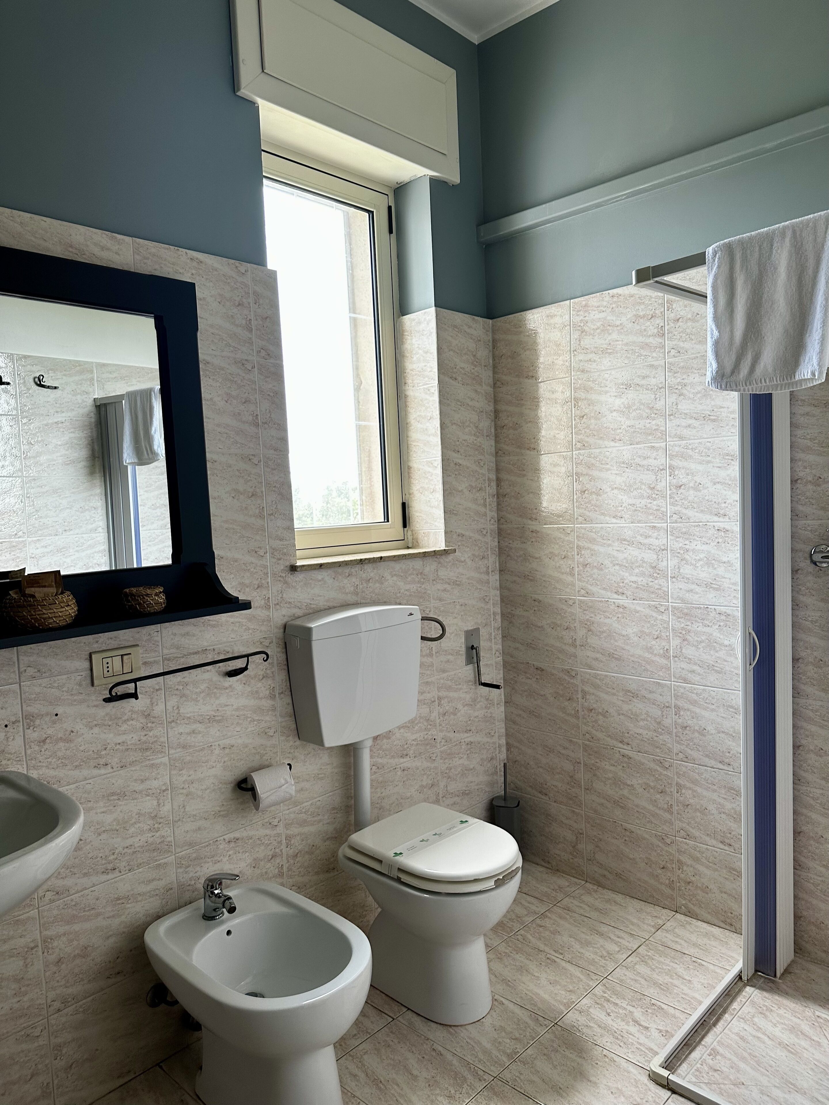 Un baño con bidé, inodoro, lavabo y ventana.