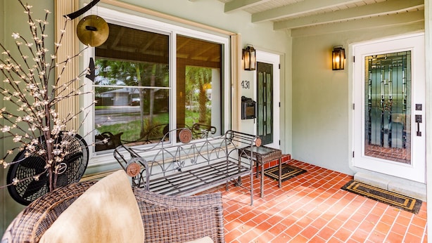 A porch with a bench, a wicker chair, a decorative plant, and a door with the number 131. - Uhost AI | Hollywood Garden 1BR Family Spot (Hollywood)