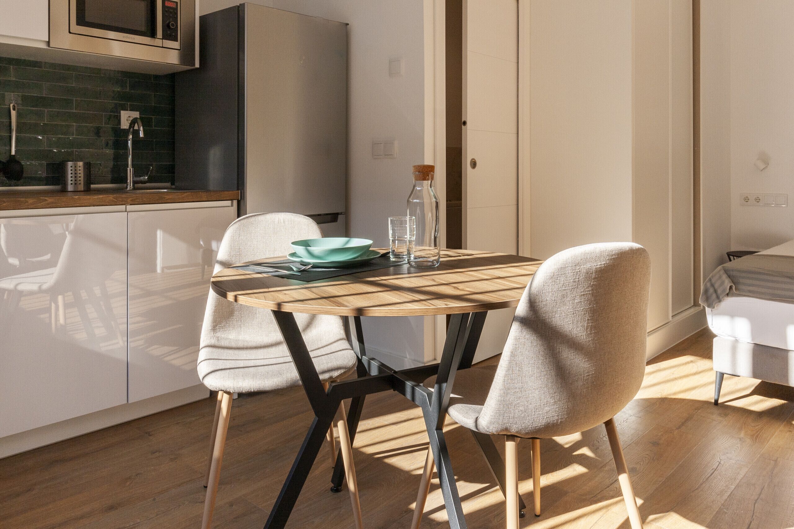 Una cocina moderna con una mesa de comedor, sillas y un microondas.