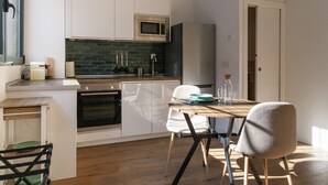 Una cocina moderna con armarios blancos, microondas, horno y un comedor con mesa y sillas.