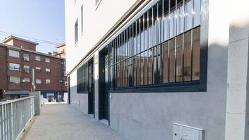 Un estrecho callejón urbano con un edificio que tiene ventanas amplias y una puerta de metal.