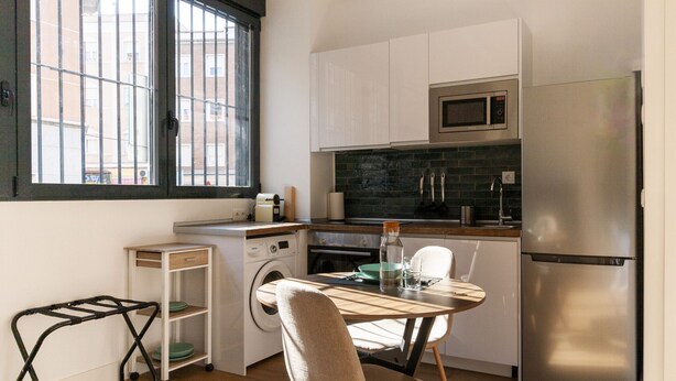 Una cocina compacta equipada con microondas, refrigerador y un pequeño comedor con mesa y sillas.
