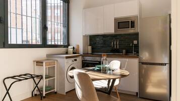 Una cocina compacta equipada con microondas, refrigerador y un pequeño comedor con mesa y sillas.