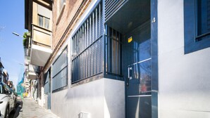 A narrow urban street with a building featuring large windows and a door with a sign.