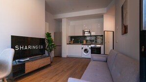 A modern living room with a grey sofa, a flat-screen TV, and a wooden entertainment unit.