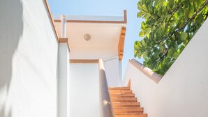 A staircase with wooden steps and white walls, leading to a covered area.