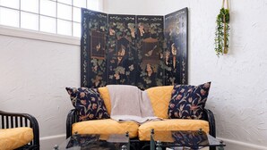 A cozy seating area with a sofa and armchairs, a glass coffee table with books, and a decorative screen with bird motifs.