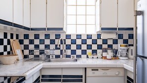 A kitchen with white cabinets, a black and white checkered backsplash, a window above the sink, and a dishwasher.