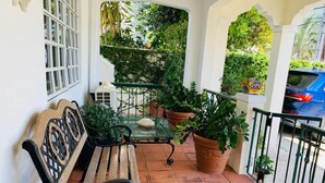 A terrace with a wooden bench, potted plants, and a tiled floor.