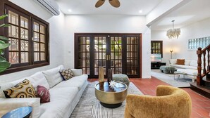 A living room with a sofa, armchair, coffee table, and a staircase. - Coastal Comfort: Spanish Villa Steps from the Sand (Santurce)