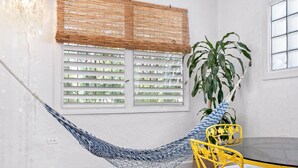 A room with a hammock, yellow chairs, a table, and a large plant. - Multi-unit beachside complex for up to 12 guests! (Santurce)