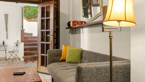 A living room with a sofa, a lamp, a bookshelf, and a door leading to an outdoor area. - Multi-unit beachside complex for up to 12 guests! (Santurce)