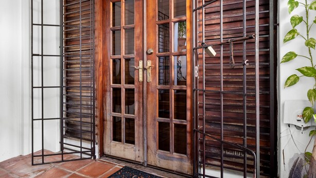 A wooden door with a metal gate, a potted plant, and a tiled floor. - Multi-unit beachside complex for up to 12 guests! (Santurce)