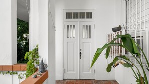A white door with a window, a balcony with a railing, and a potted plant. - Multi-unit beachside complex for up to 12 guests! (Santurce)
