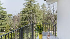 Ein Balkon mit Topfpflanze, zwei Weingläsern und einer Flasche.